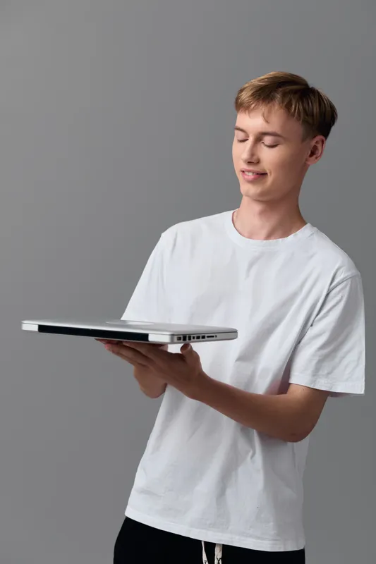 Man holding a laptop with screen visible, casual studio setting conveys technology and education vibe, modern workspace, focused expression, learning and demo of digital skills