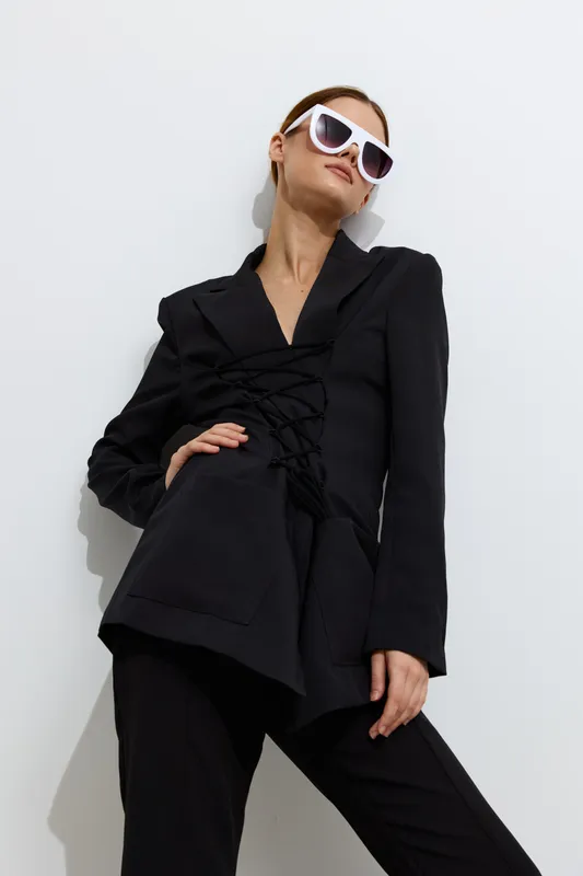 Fashion woman in black stylish suit and white sunglasses poses confidently against white background, showcasing modern beauty with chic attitude and sleek design.