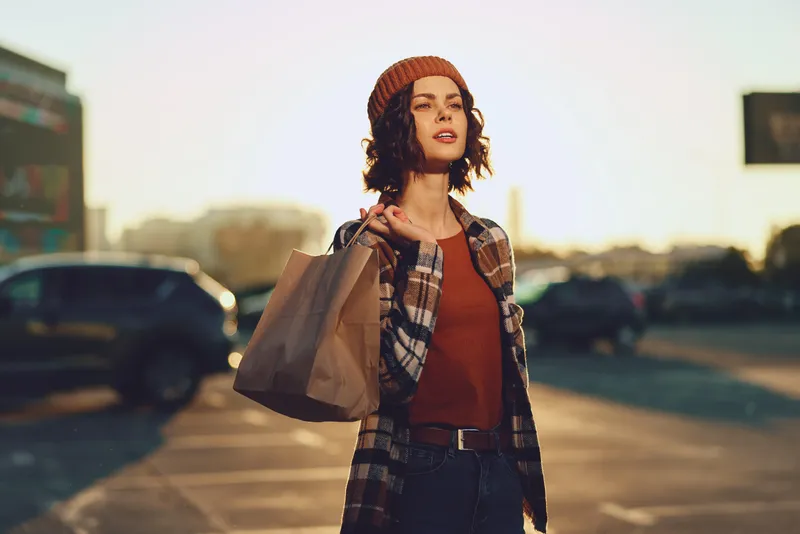 Woman shopping in urban street portrait at golden hour, candid fashion moment with bag and warm golden hour glow, authenticity and candid lifestyle evoking mindful living and emotional storytelling.