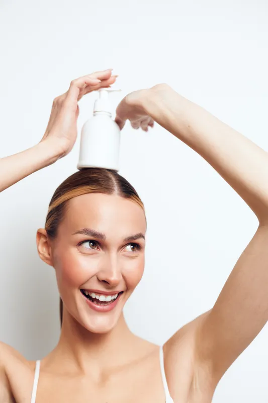 Woman haircare pump bottle apply hands above head smiling in a close up beauty routine on white background, concept for self care and personal grooming