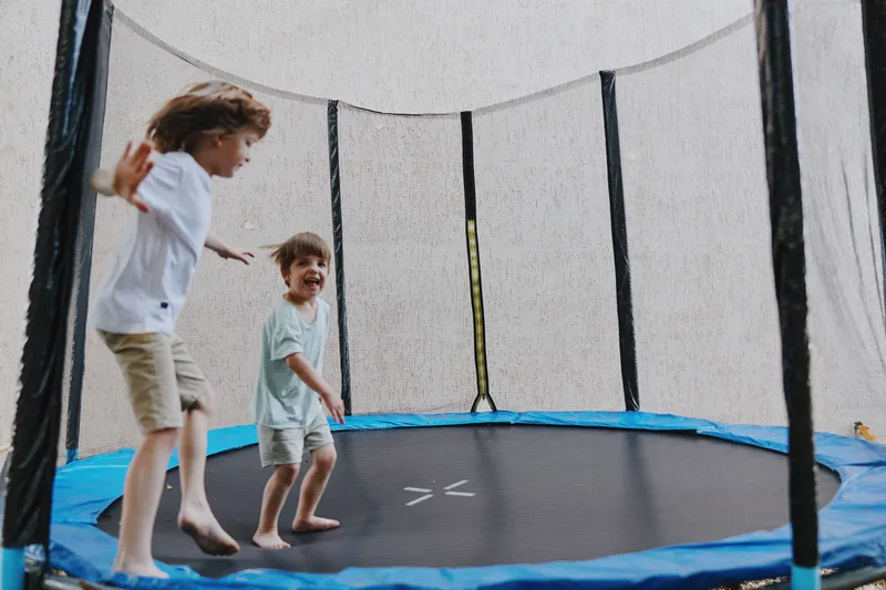 Joyful children jumping on a trampoline, enjoying playful moments as they laugh and share fun together, creating happy memories in a sunny, vibrant environment.