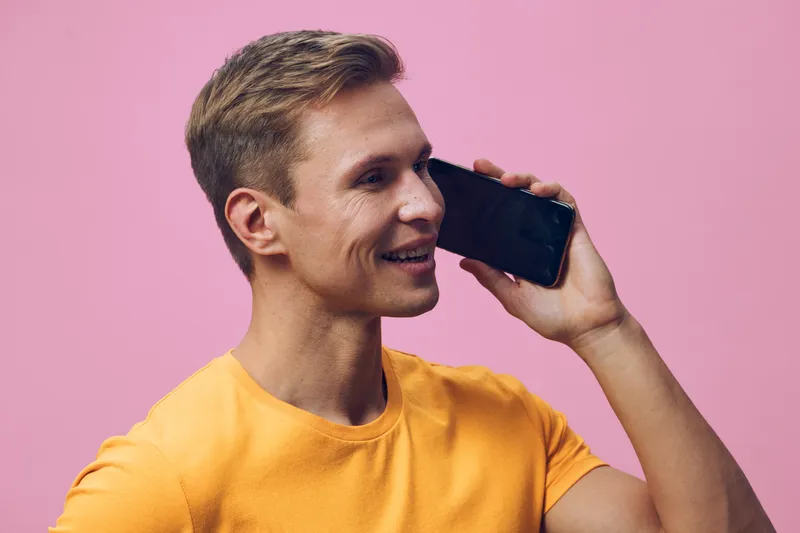 smiling young man talking smartphone yellow t-shirt purple background digital nomad concept communication technology interaction casual lifestyle