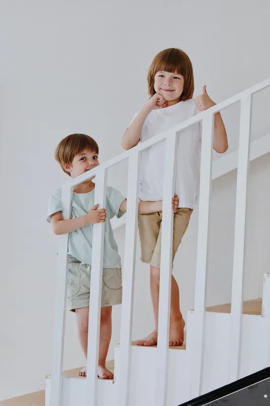 Happy children climbing stairs, smiling faces, playful mood, modern interior, cheerful environment.