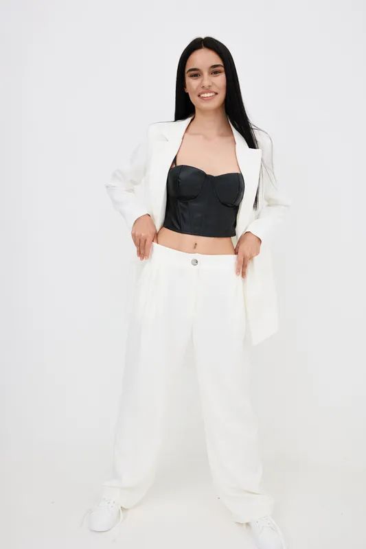 confident woman wearing white suit and black corset standing with smile, stylish clothing, modern fashion, casual pose, isolated background, young adult female
