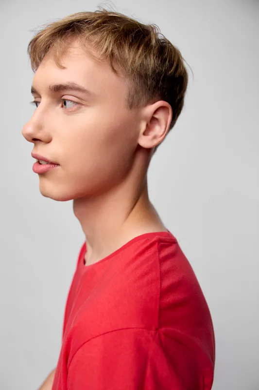 Boy, side view, profile, youth, red shirt, young male, calm expression, studio lighting, neutral background, clean composition, simple setup, fashion concept, lifestyle image, education theme,