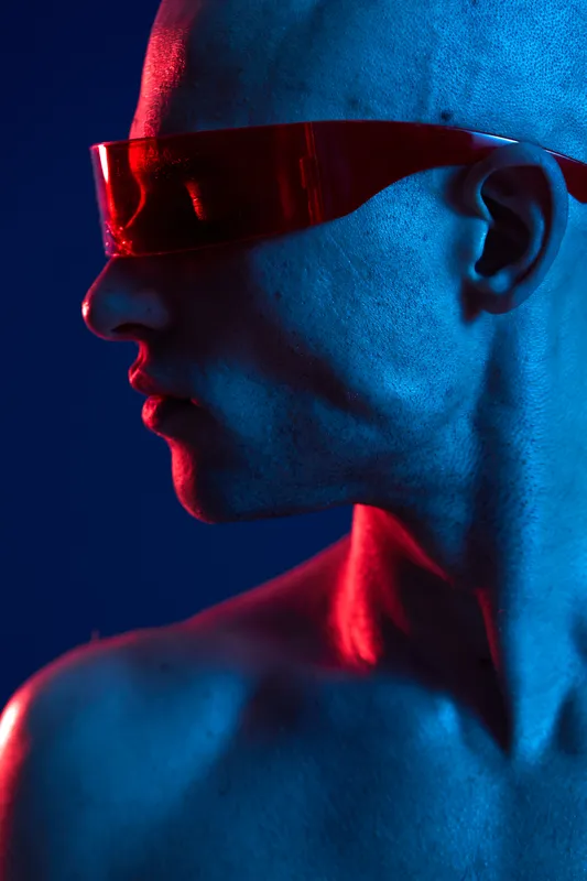 A striking portrait of a man with unique sunglasses, showcasing a fusion of blue and red lighting. This captivating image highlights bold features and modern aesthetics.