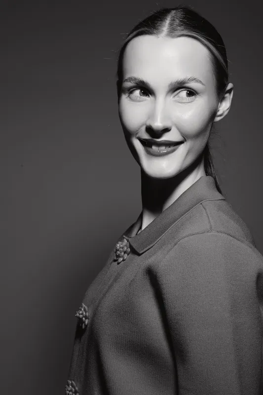 Portrait of a smiling white woman with light skin looking sideways, wearing a textured jacket in black and white photography.