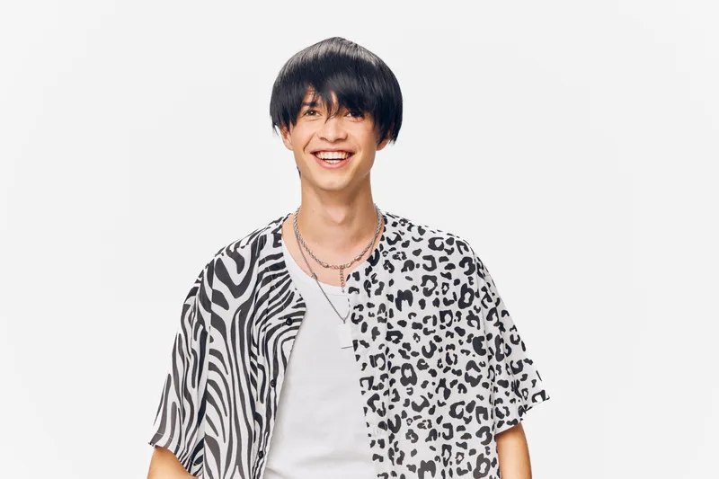 smiling man wearing a mixed animal print shirt and white t-shirt, short black hair, joyful expression, isolated on white background in studio lighting