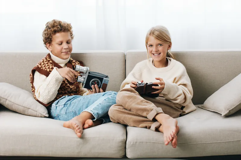 Authentic scene showing two children on a cozy sofa, sharing a playful moment of game play and creativity, capturing everyday school life and home lifestyle.
