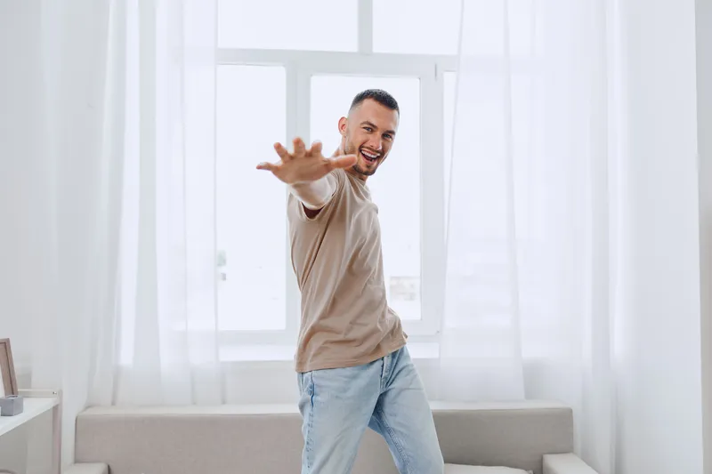 Happy man engaging in a moment of self-care, embodying soft masculinity and authentic imperfection in a relaxed home environment, promoting mental well-being.
