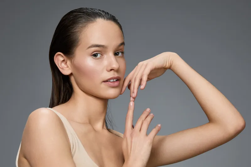 Portrait of a beautiful woman with sleek hair and natural makeup, exuding confidence and elegance against a minimalist gray background