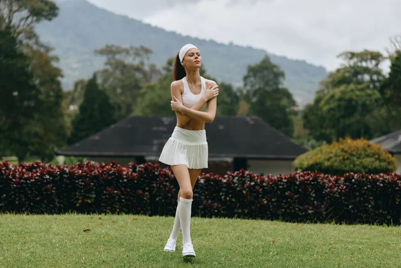 Young athletic model in a sporty outfit, showcasing confidence and vitality against a vibrant green background, representing fitness, health, and summer activities