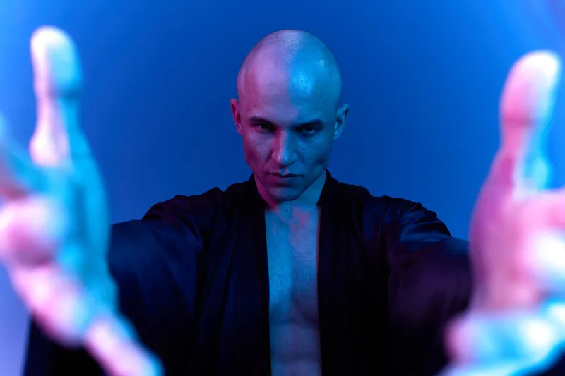 Male performer expressing intensity in a dramatic pose, showcasing emotion and energy with a blend of blue and purple lighting. Black and white contrasts enhance impact.