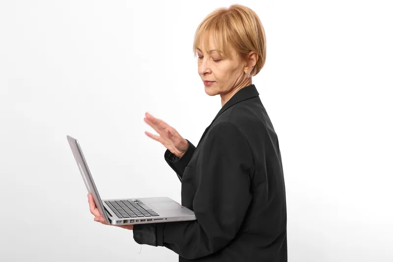 Woman with laptop in a bright studio, business communication with hand gesture, technology focus, thinking expression and stress, side view on white background.