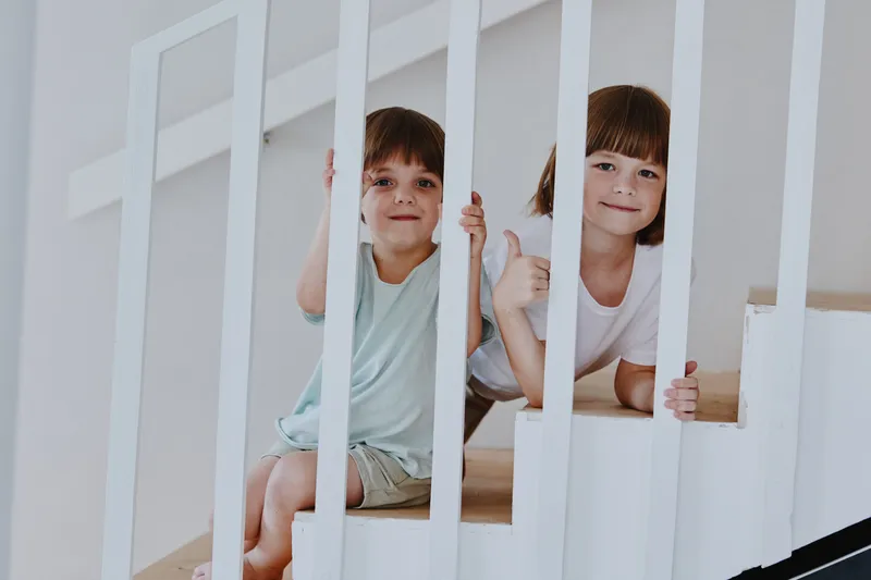 Cheerful children playing on the stairs, presenting joyful expressions while having fun together and enjoying a moment of childhood playfulness. ###