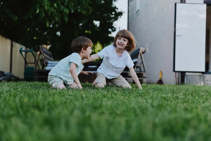 Happy children playing outdoors on fresh green grass, enjoying their summer day filled with laughter and joy, creating cherished memories together in the sun.