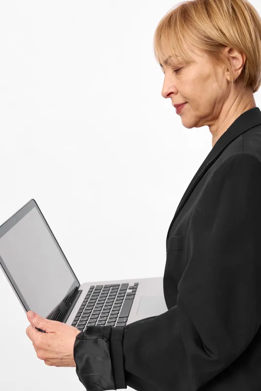 Woman laptop profile adult business typing indoors white technology studio, holding computer, focused typing expression, office style, clean studio lighting, white background