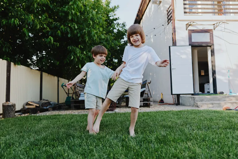 Playful children enjoying a sunny day, running on green grass with carefree expressions and bright outfits, capturing the joy of childhood.