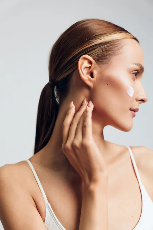Woman touches her face and cheek for skincare beauty on a side profile, showing skin care concept. White background, closeup portrait, soft light, gentle calm mood.