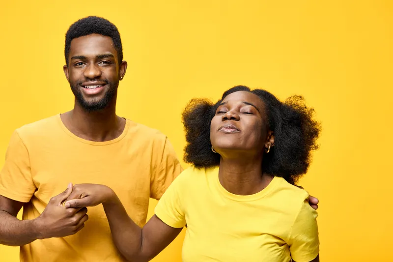 Joyful young African couple in matching yellow outfits, expressing love and happiness against a bright yellow background, perfect for seasonal celebrations