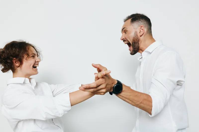 A professional businessman on an isolated color background expresses strong enthusiasm while engaging in a confident handshake, showcasing leadership, energy, and dynamic motivation.
