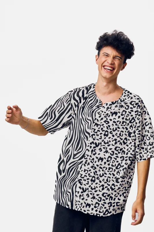 smiling man wearing black and white animal print shirt laughing joyfully against white background, casual style, youth fashion, happiness expression