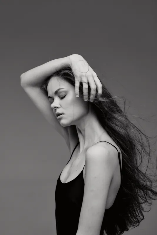 Black and white portrait of a woman with long hair posing gracefully with closed eyes and a delicate expression.