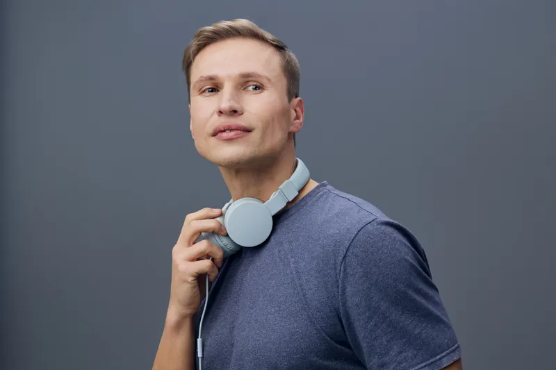 thoughtful man with headphones around neck look up wear blue t-shirt isolated on grey background studio portrait digital nomad concept