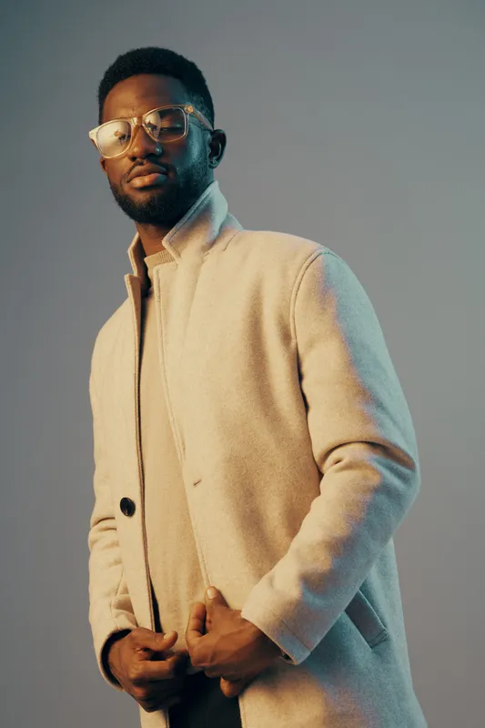 Stylish young man in a fashionable coat, exuding confidence with a neutral background and soft lighting, ideal for fashion and lifestyle concepts