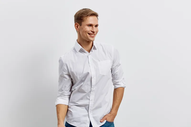 Smiling man in white dress shirt casual pose stand isolated on plain white background studio portrait. People lifestyle concept