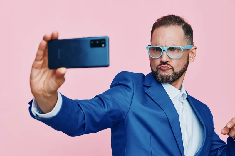 Professional businessman with a confident expression takes a self portrait against an isolated colored backdrop, conveying ambition, focus, and a dynamic corporate mood.
