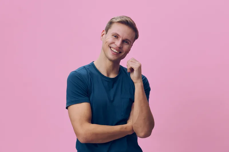 smiling young caucasian man casual blue t-shirt looking camera digital nomad concept isolated pink background cheerful lifestyle portrait