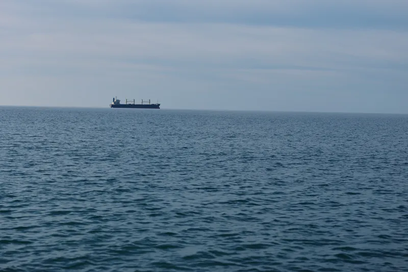 Sea and distant ship on a calm ocean horizon over vast water, capturing a tranquil maritime scene with open water and quiet solitude at sea