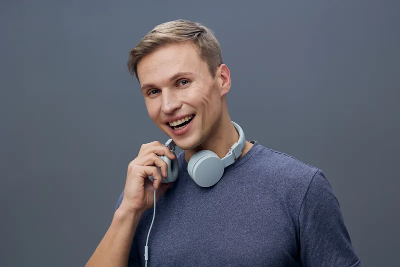 smiling man with headphones hold audio jack wear casual sweater look camera studio portrait digital detox mental health concept