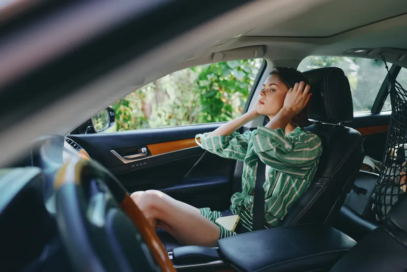 Car, driver, woman, smile a cheerful woman sits in the driver's seat with her hand on the steering wheel, radiating confidence, joy, and readiness for a journey in a warm interior.