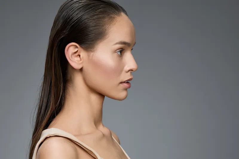 Elegant profile portrait of a young woman with wet hair, showcasing natural beauty and a neutral background, perfect for fashion and beauty concepts