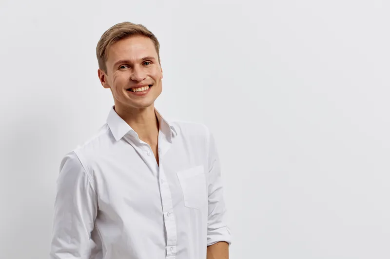 Smiling man in white shirt with AI chat concept use phone standing isolated on light background happy confident young caucasian male digital communication technology