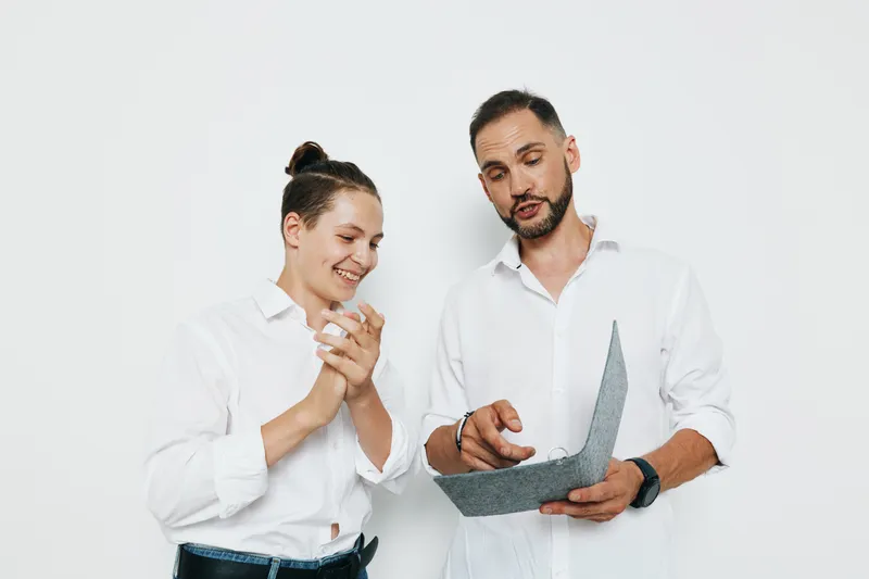 A professional man and colleague review a document against an isolated colored background, showing business focus, emotional engagement, and confident teamwork.