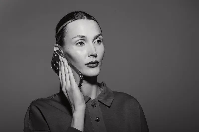 Portrait of a young white woman with light skin talking on mobile phone. Studio lighting highlights her facial features and serious expression.