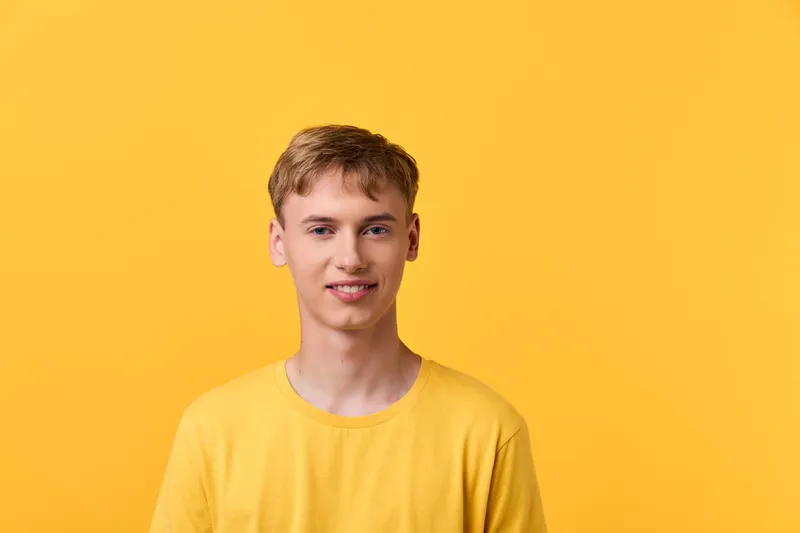 Smiling man in a yellow tee stands before a vivid yellow backdrop, casual style, front view, studio shot, conveying a cheerful mood and approachable vibe for lifestyle or marketing projects
