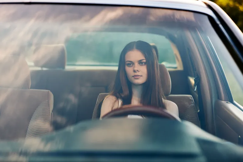 Thoughtful young woman in a car contemplating life, featuring warm tones and a serene background, perfect for personal reflection and self-discovery themes.