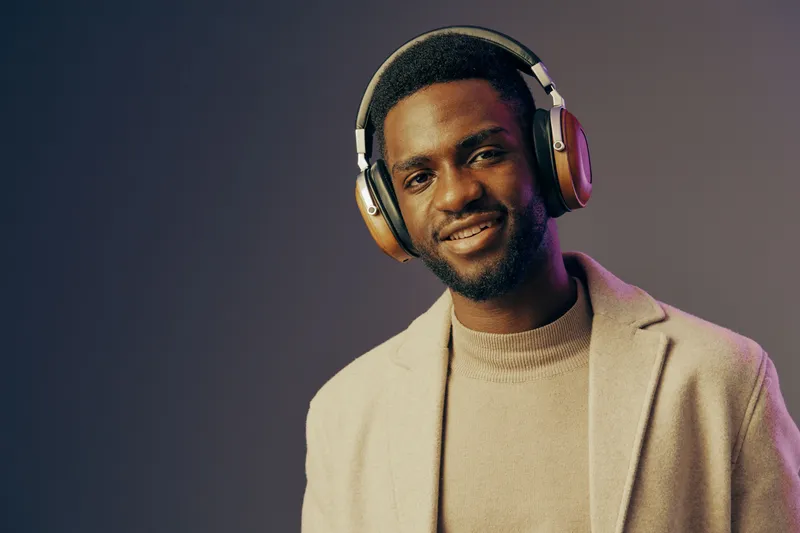 Stylish young Black man wearing headphones, smiling confidently against a gradient background, showcasing a modern urban lifestyle and vibrant energy