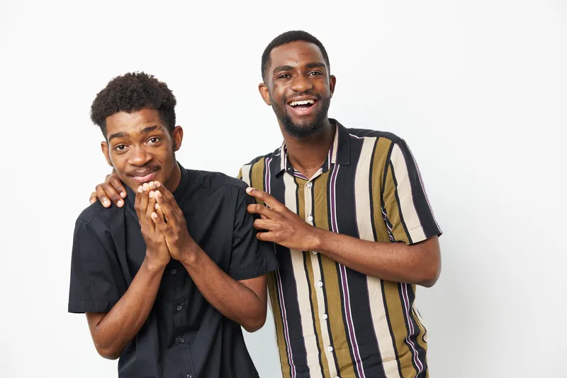 Two cheerful African American men posing together with friendly smiles, creating a warm and inviting atmosphere, perfect for conveying joy and friendship.
