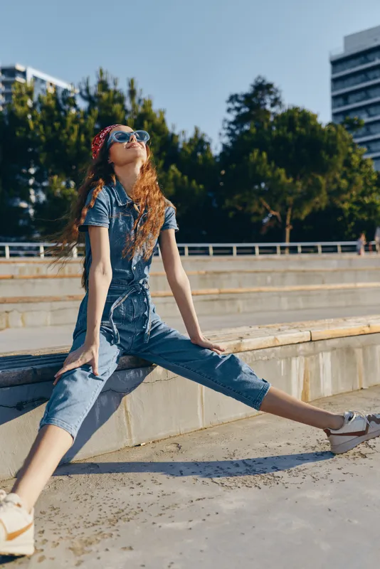Lifestyle woman in modern boho-western denim street style poses confidently outdoors with film color tones, exuding relaxed and trendy urban energy.