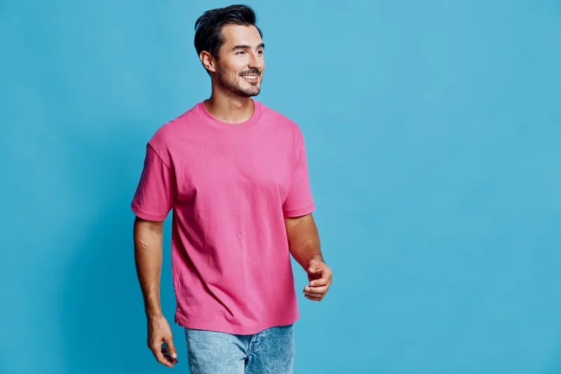 Full body smiling happy cheerful young man wear pink t-shirt walk confidently look camera isolated on bright blue background studio portrait. People lifestyle concept