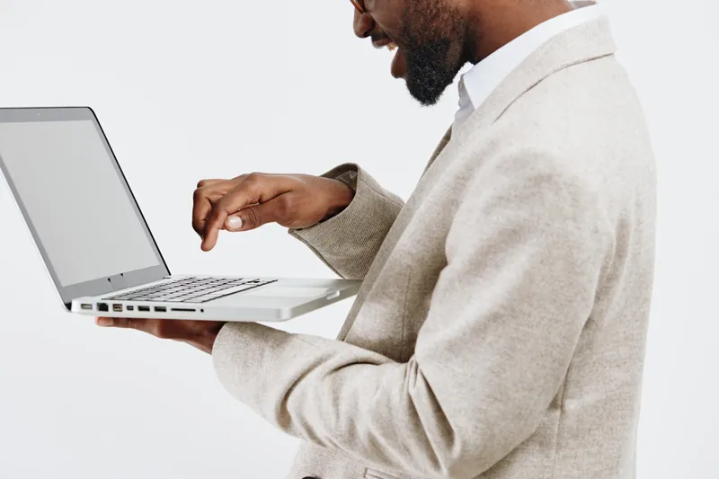 Professional man using laptop computer in office setting, focusing on technology, work, and business development with a teamwork concept, isolated on white background, modern style.
