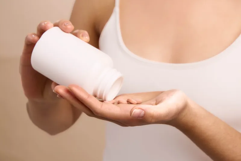 asian woman applies lotion from a white bottle in a calm indoor setting. closeup of hands and smooth skin captures a skincare moment, radiating wellness, care, and a gentle, serene atmosphere.