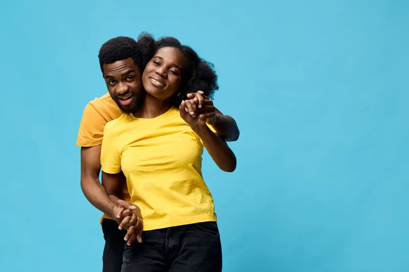 Happy couple in matching yellow shirts against a bright blue background, showcasing joy and connection, perfect for social themes or lifestyle content