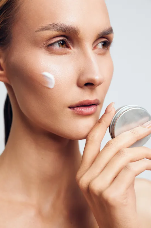 Woman applying cream for skincare on face closeup, beauty wellness selfcare concept, cotton pad and jar, soft studio light, smooth moisturizer hydration texture