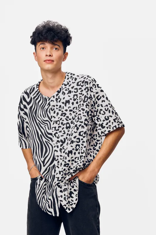 young man with patterned shirt posing casually with hands in pockets, isolated white background, modern hairstyle, relaxed expression, stylish clothing